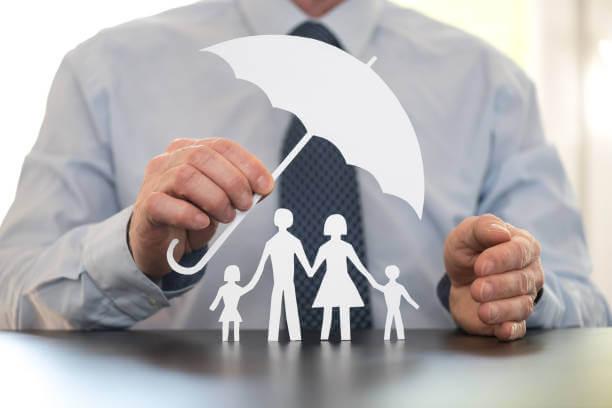 Petite famille en papier couvert d'un parapluie indiquant la couverture d'assurance
